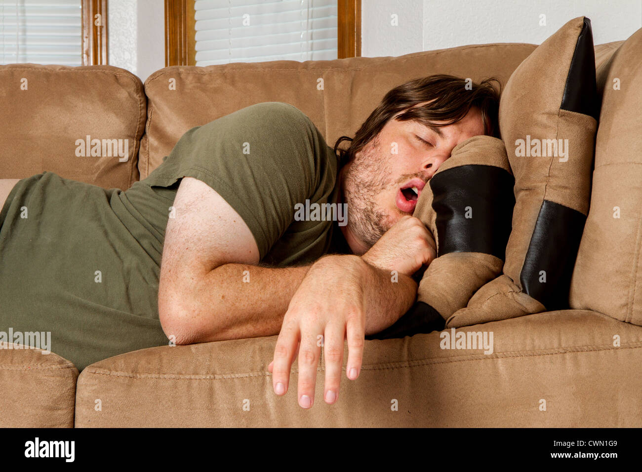 Er ist eingeschlafen Mund offen und Arm nur über die Seite der Couch geworfen. Stockfoto