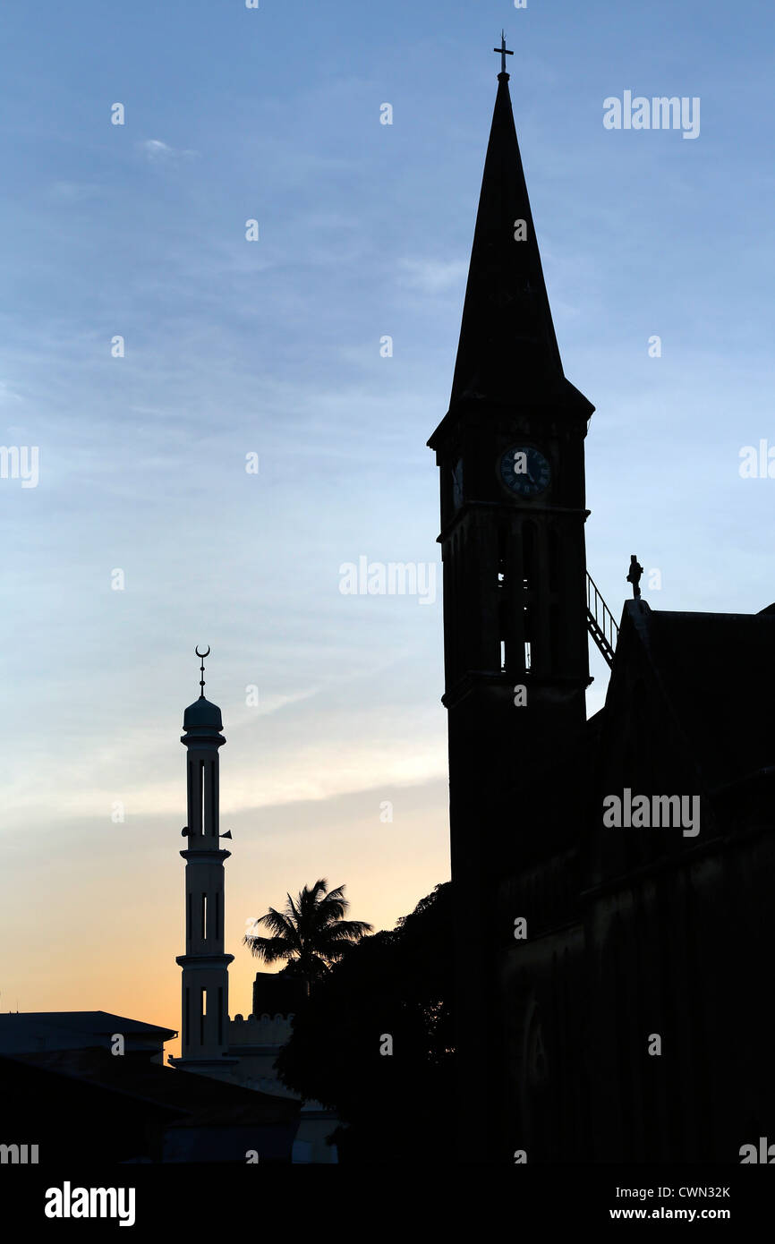 Glockenturm der anglikanischen Kathedrale auf dem Gelände des ehemaligen Sklavenmarkt und Moschee Minarett in Stonetown, Sansibar, Tansania Stockfoto
