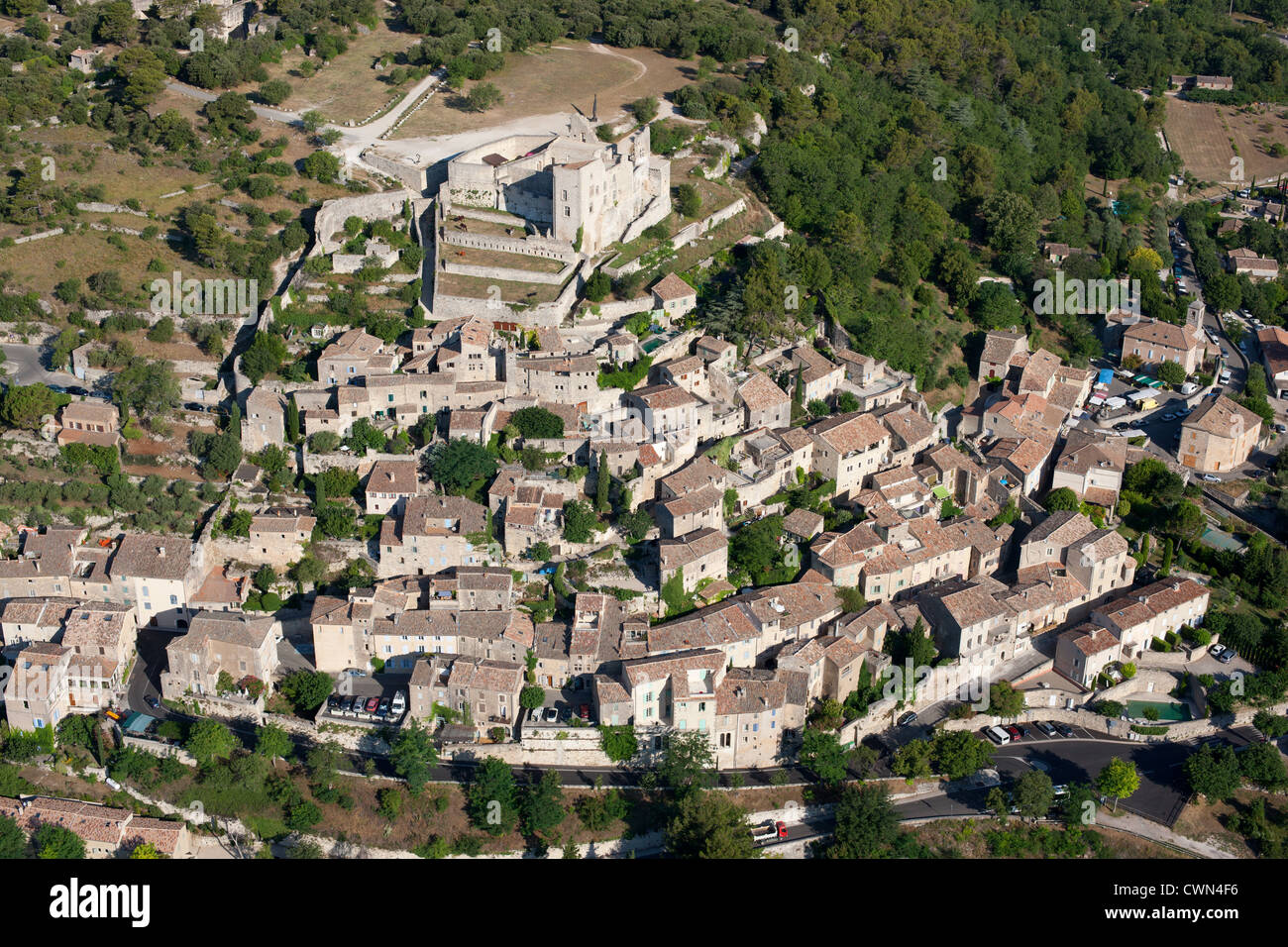 LUFTAUFNAHME. Ein mittelalterliches Dorf auf einem Hügel, gekrönt von einer Burg. Lacoste, Lubéron, Vaucluse, Provence, Frankreich. Stockfoto