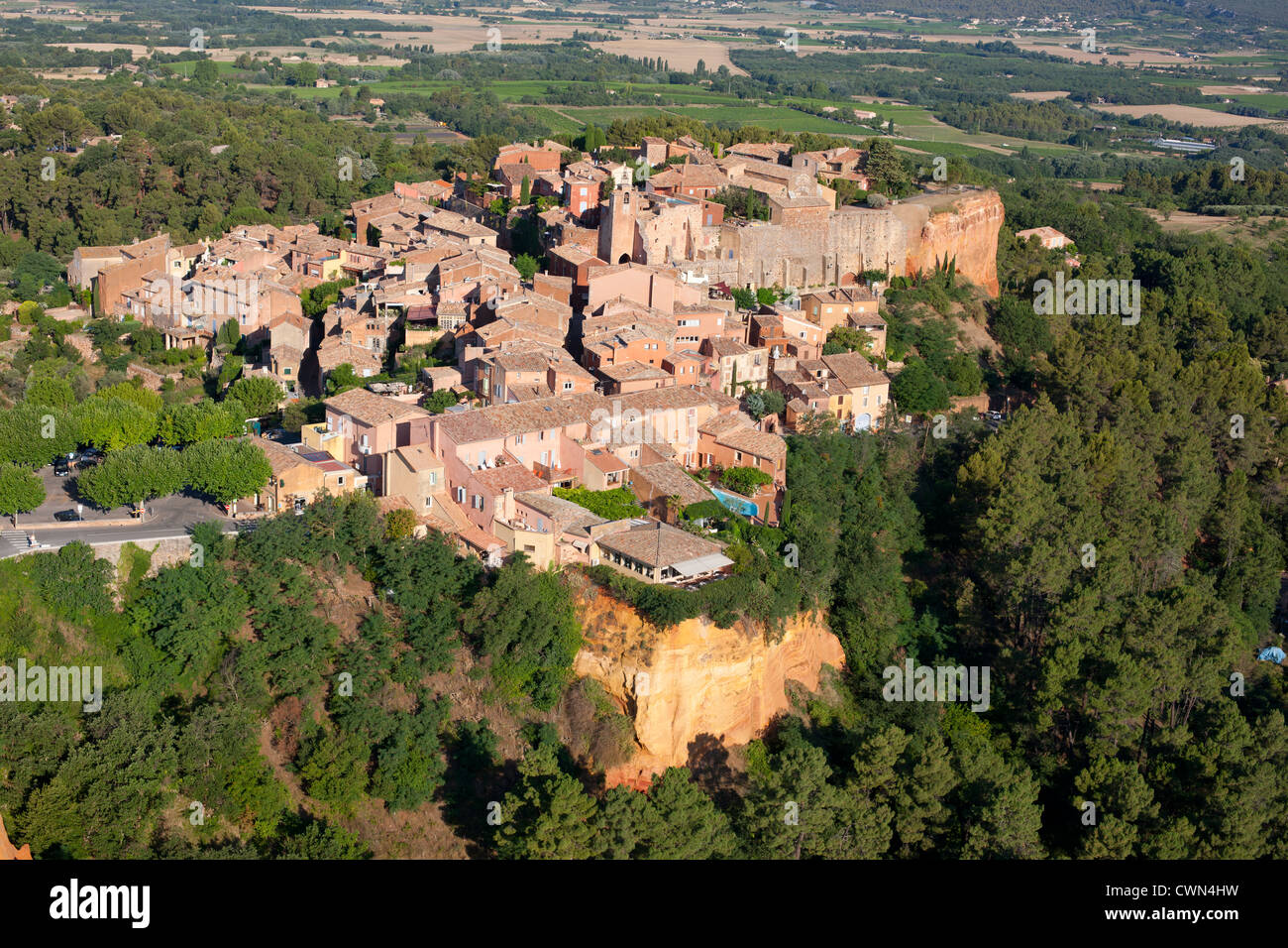 LUFTAUFNAHME. Mittelalterliches Dorf auf einer rot-ockerfarbenen Lehmklippe. Roussillon, Vaucluse, Provence, Frankreich. Stockfoto