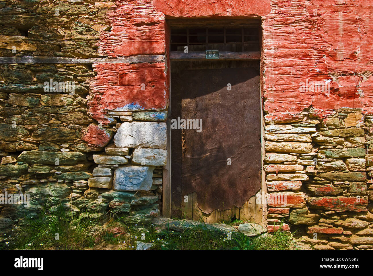 Bunte Fassade ein altes Landhaus aus Stein mit verwitterten Metalltür und Hausnummer auf Pilion Halbinsel, Thessalien, Griechenland Stockfoto