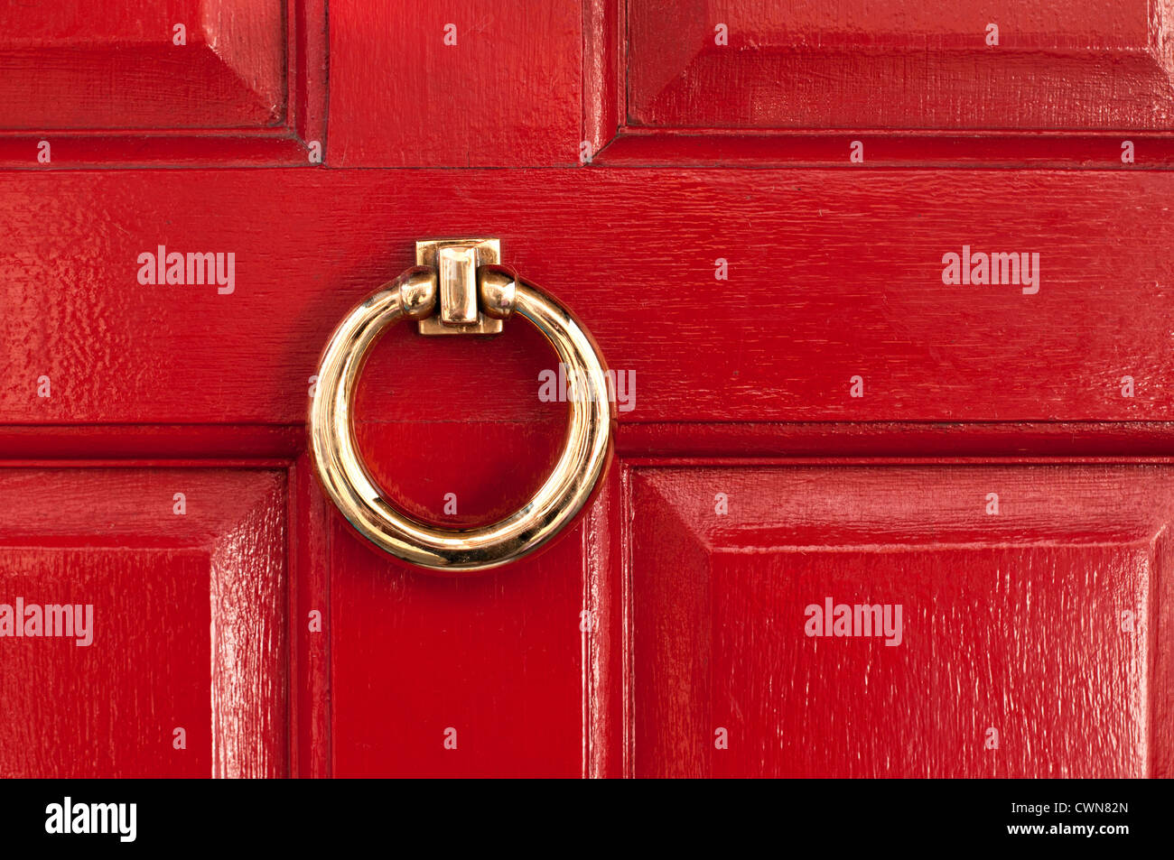 Glänzend poliertem Messing ring Türklopfer auf Rote Glanzoberfläche Tür lackiert, London, England, Großbritannien Stockfoto