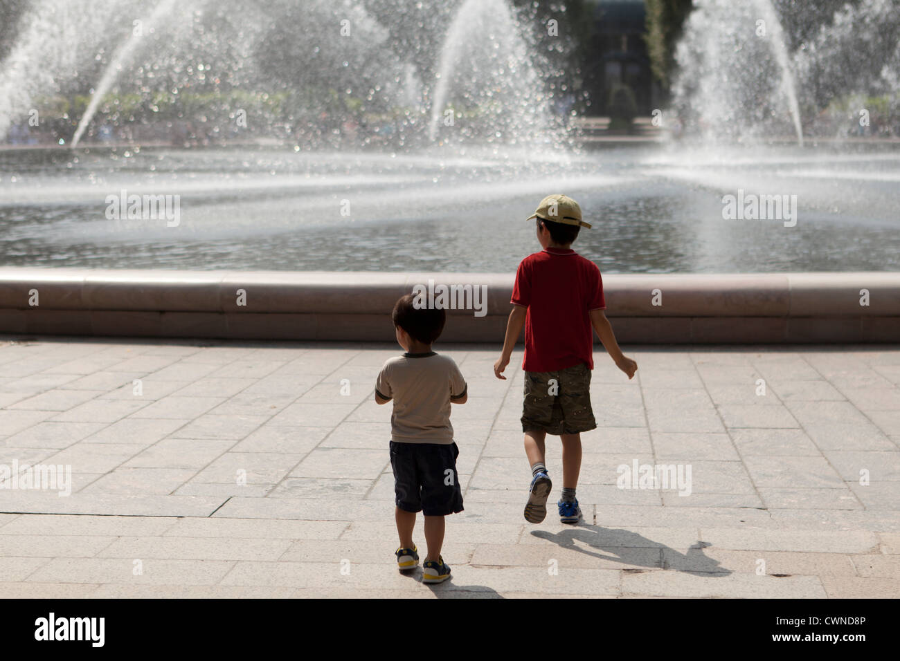 Junge Burschen, die zu Fuß in Richtung eines öffentlichen Brunnens Stockfoto