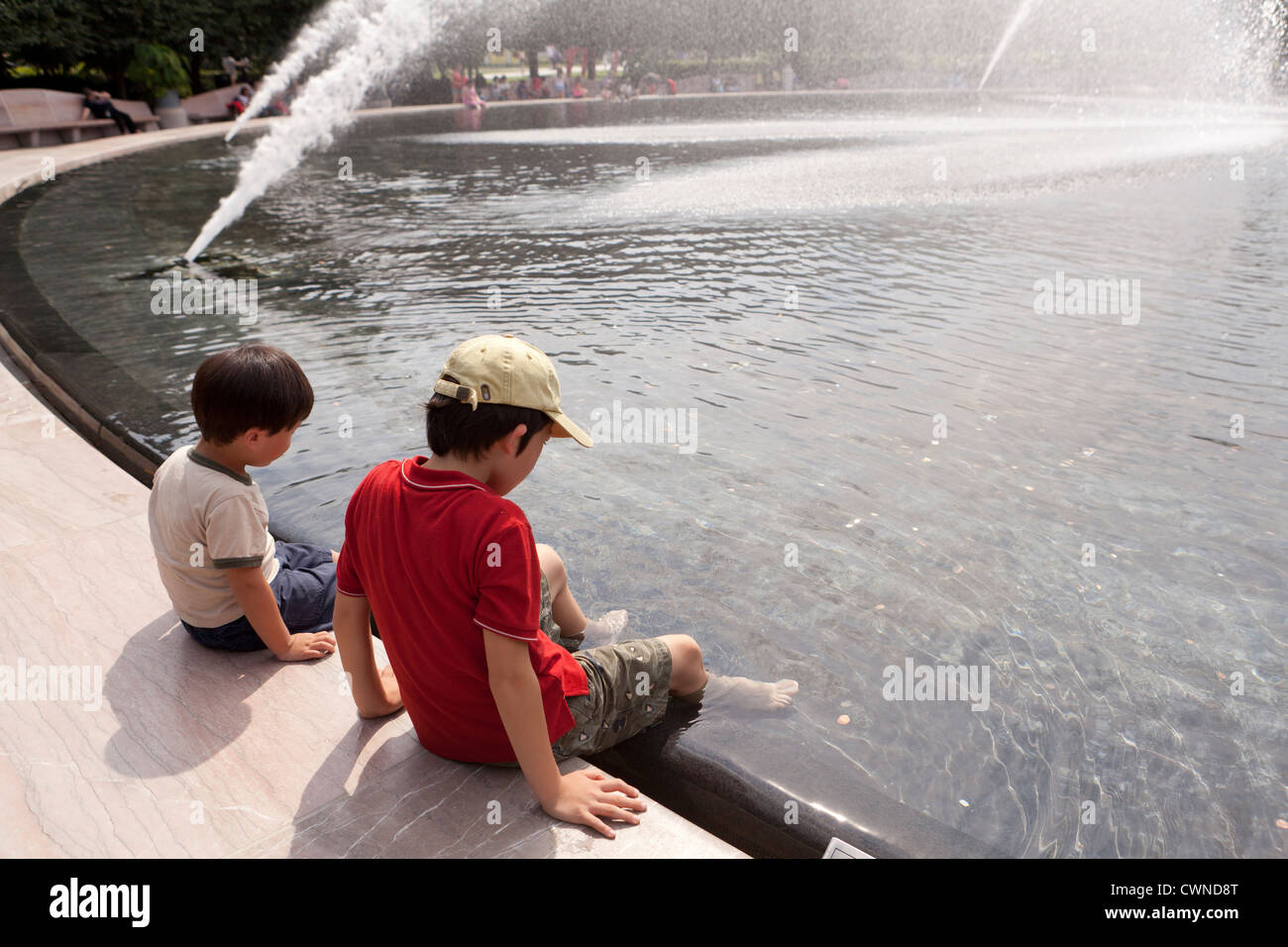 Junge Burschen sitzen an einem öffentlichen Brunnen Stockfoto