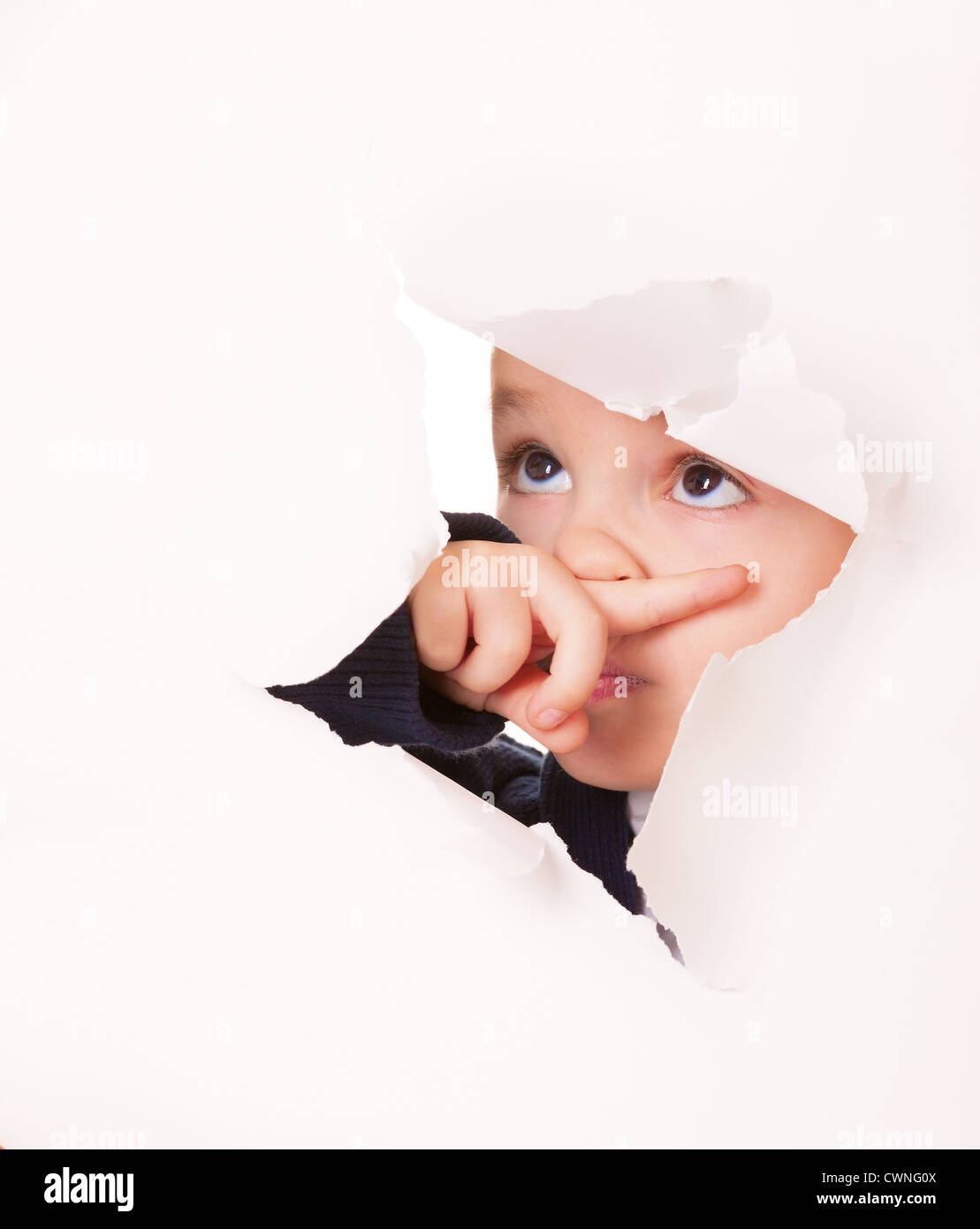 Schuldig Kind blickt durch ein Loch im Weißbuch Stockfoto