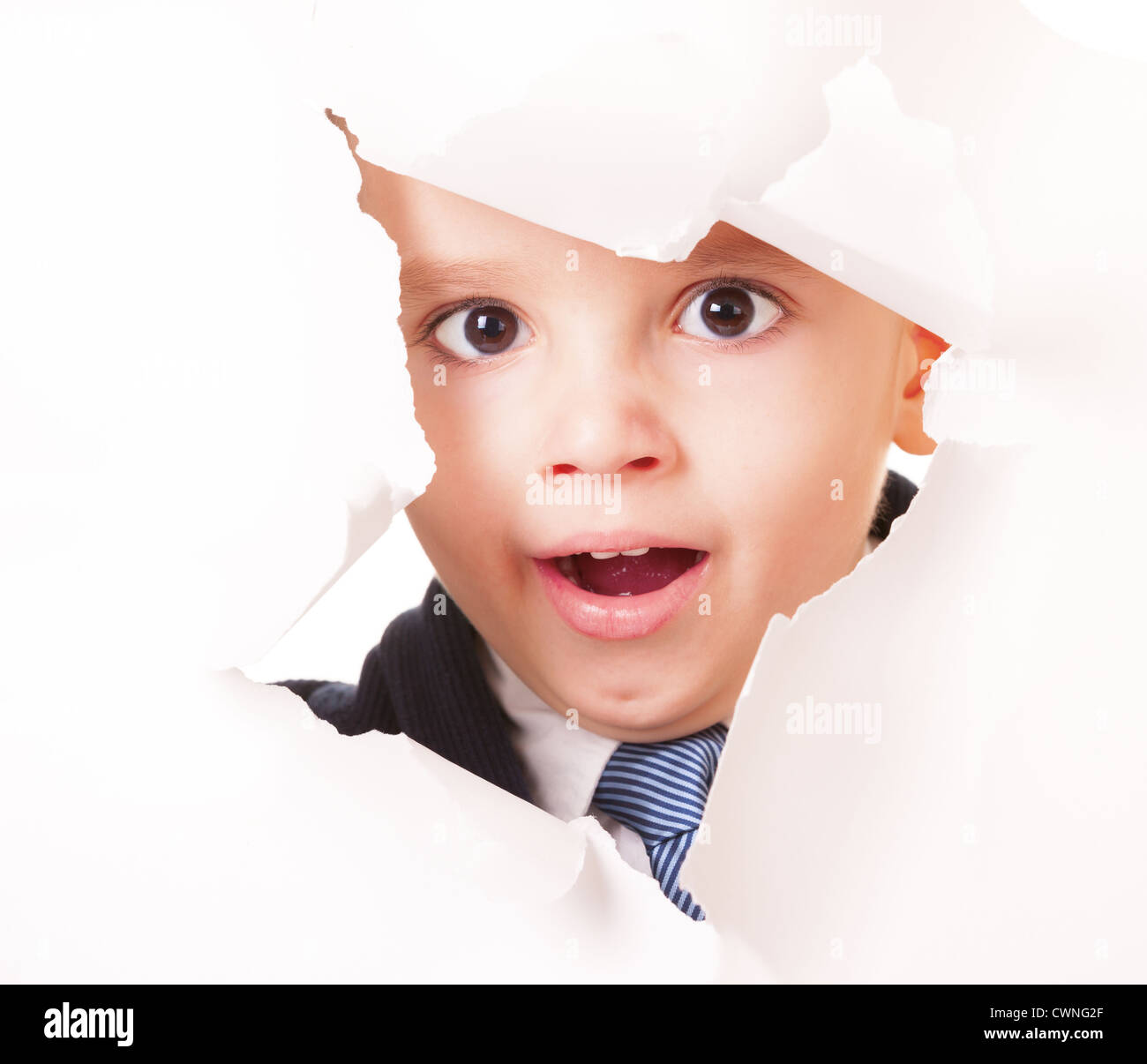 Gähnende Kind blickt durch ein Loch im Weißbuch Stockfoto