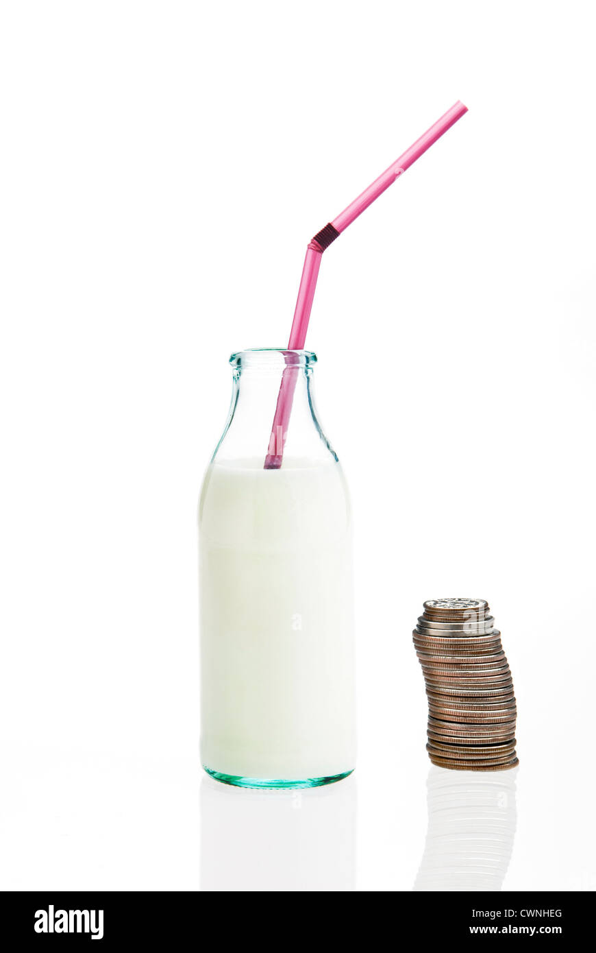 Milch in einer Flasche mit einem Strohhalm neben einem Stapel von Münzen, gesundes Schulessen, isoliert auf weißem Hintergrund Stockfoto