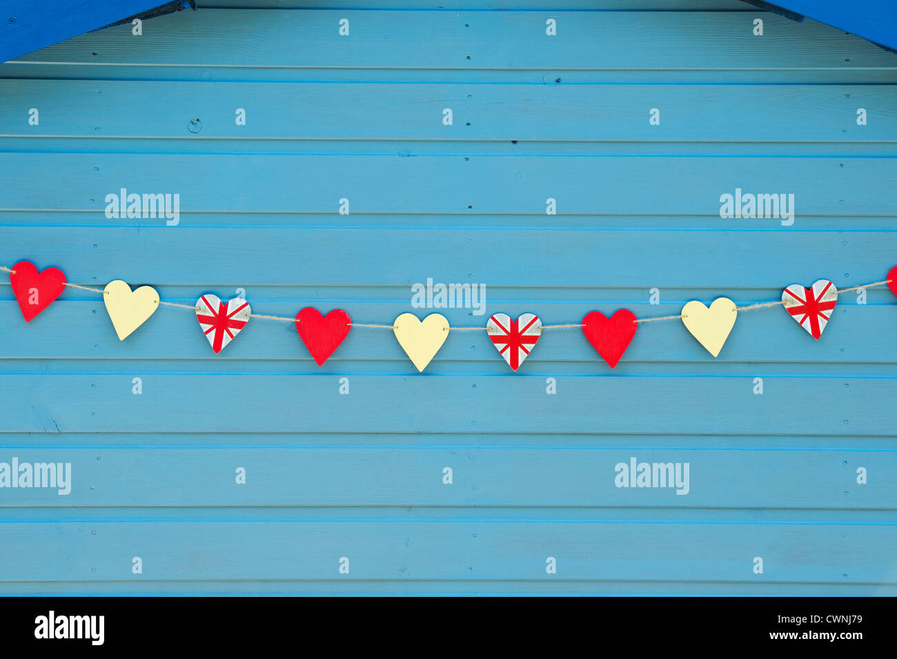Holz- Union Jack Herzen formen, aufgereiht auf einem blauen Gartenhaus. England Stockfoto