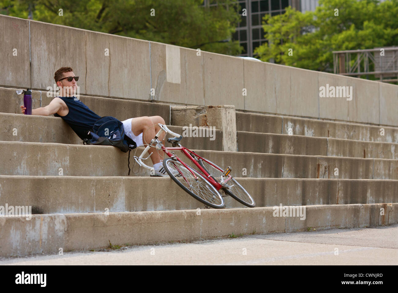 Junger Mann ruht auf konkrete Schritte nach dem Training auf dem Fahrrad In Chicago Stockfoto