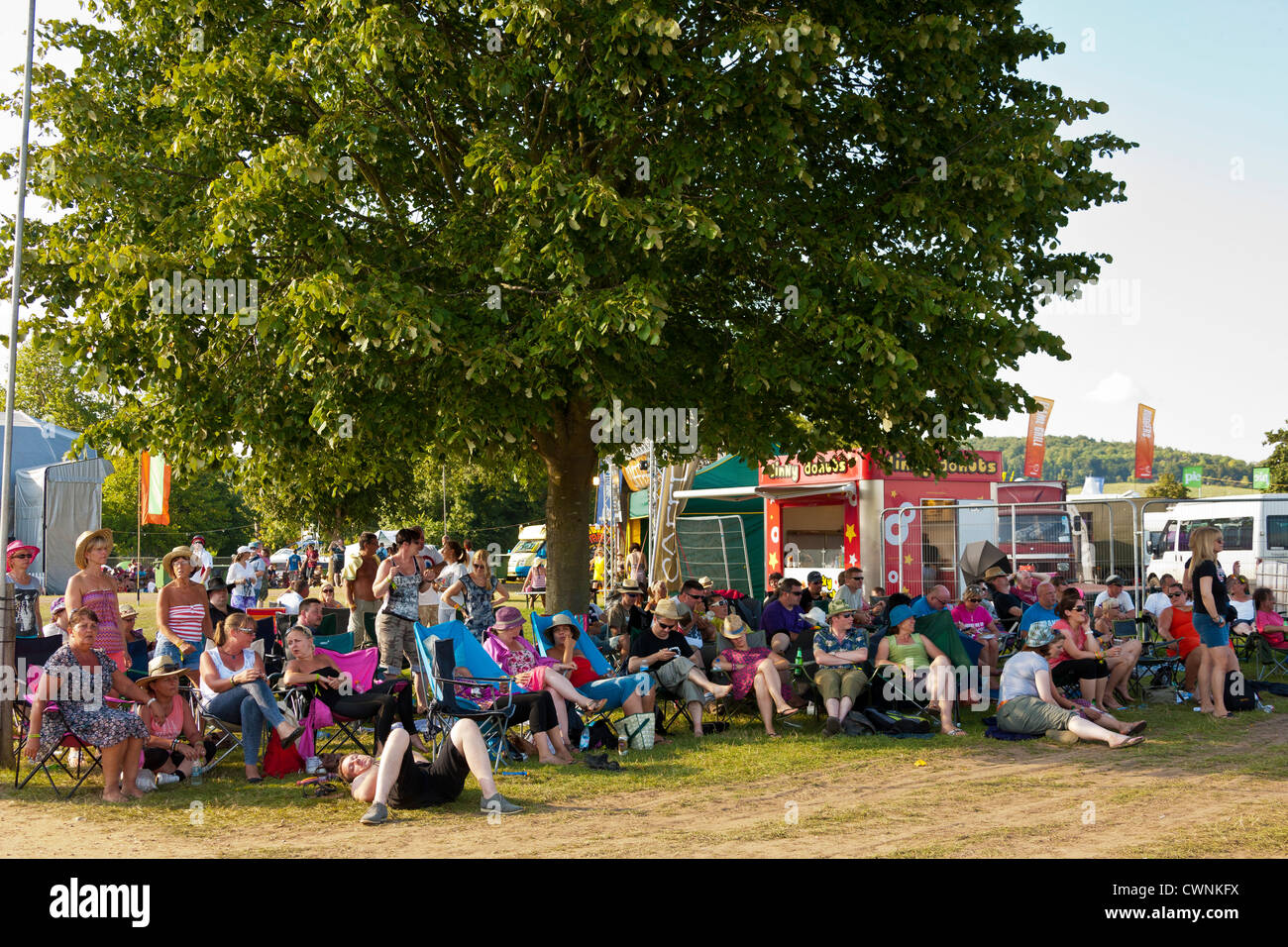 Festivalbesucher finden Zuflucht vor der Sonne und Hitze unter einem Baum auf den Rücklauf Festival Henley on Thames 2012. JMH6057 Stockfoto