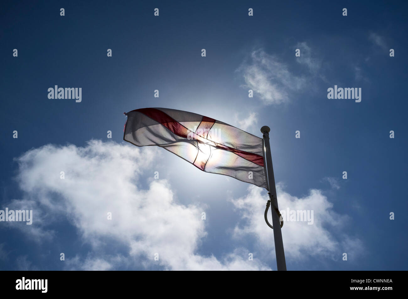 Ein Kreuz von St. George Flagge deckt die Sonne gegen ein strahlend blauer Himmel mit flauschigen Wolken Stockfoto
