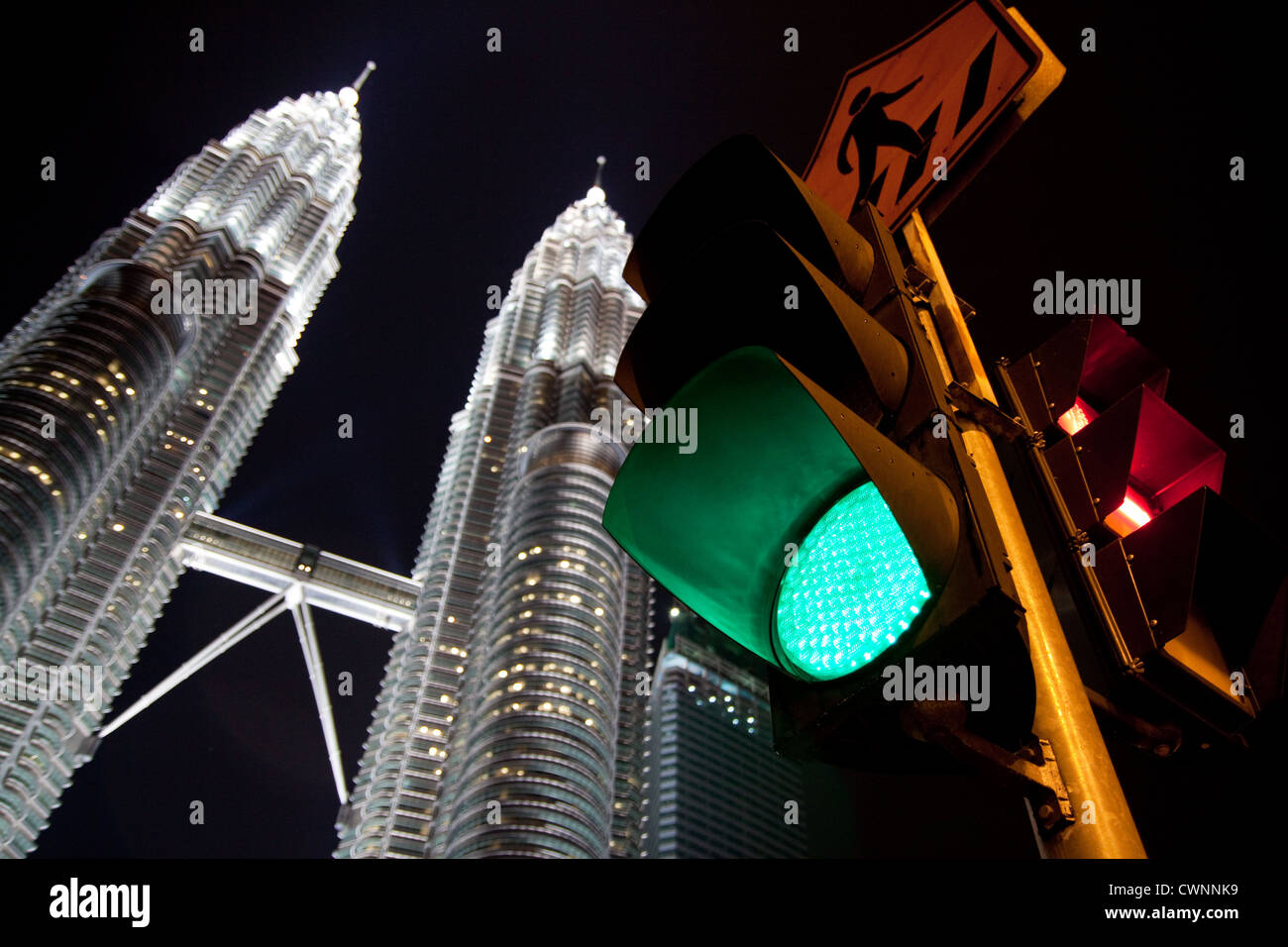 Low Angle View Ampel mit hoch aufragenden Petronas Towers im Hintergrund. selektive Fokus auf die grüne Ampel mit beleuchteten Petronas Stockfoto