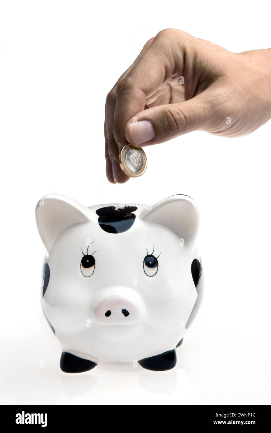 Münze Fallenlassen in ein Sparschwein auf weißem Hintergrund Stockfoto