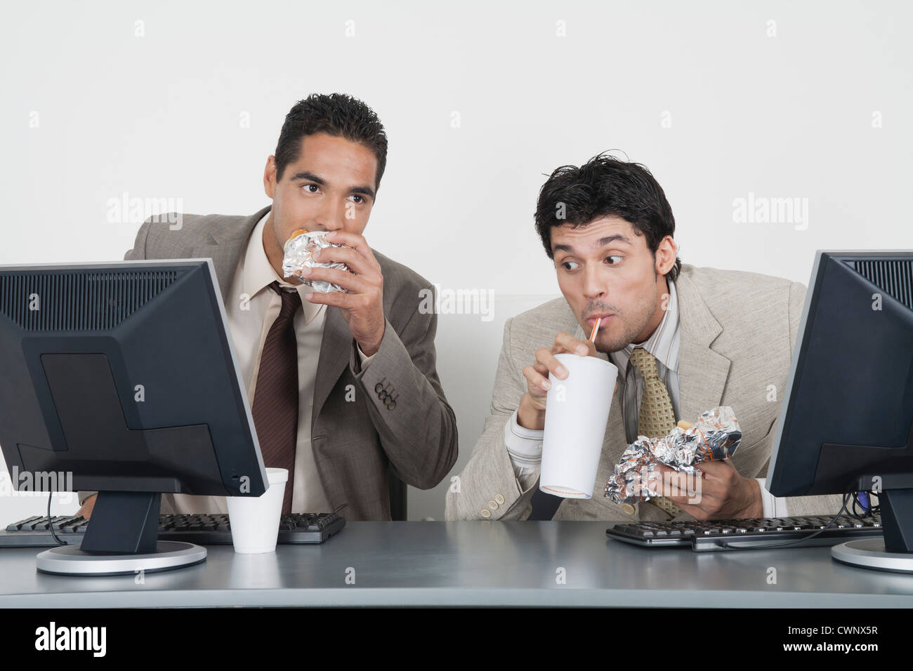 Geschäftsleute, die Essen Fast Food am Schreibtisch im Büro Stockfoto