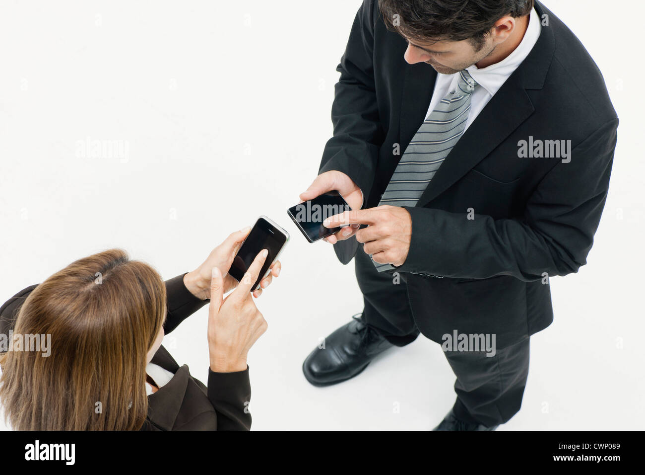 Verwenden Geschäftsfrau und Geschäftsmann von Angesicht zu Angesicht stehen beide smartphones Stockfoto