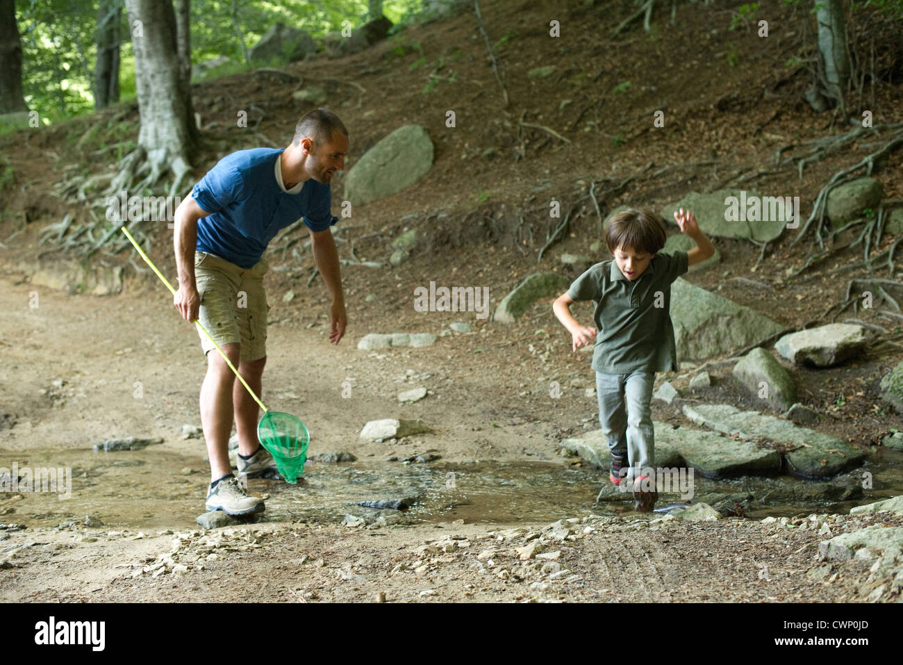 Vater und Sohn in Wäldern, junge, springen über stream Stockfoto