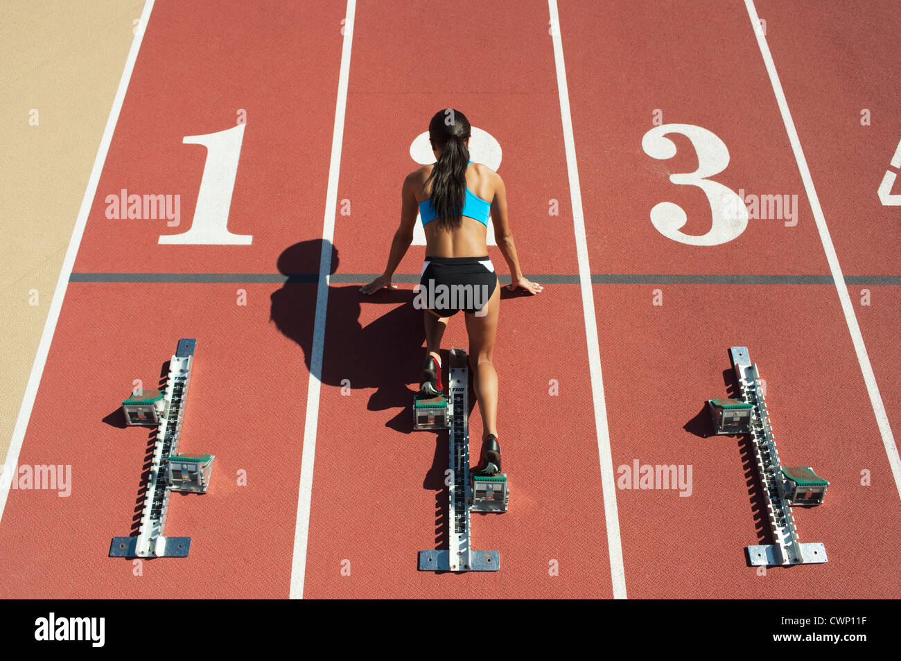 Sportlerin in Startposition auf Laufstrecke, Rückansicht Stockfoto