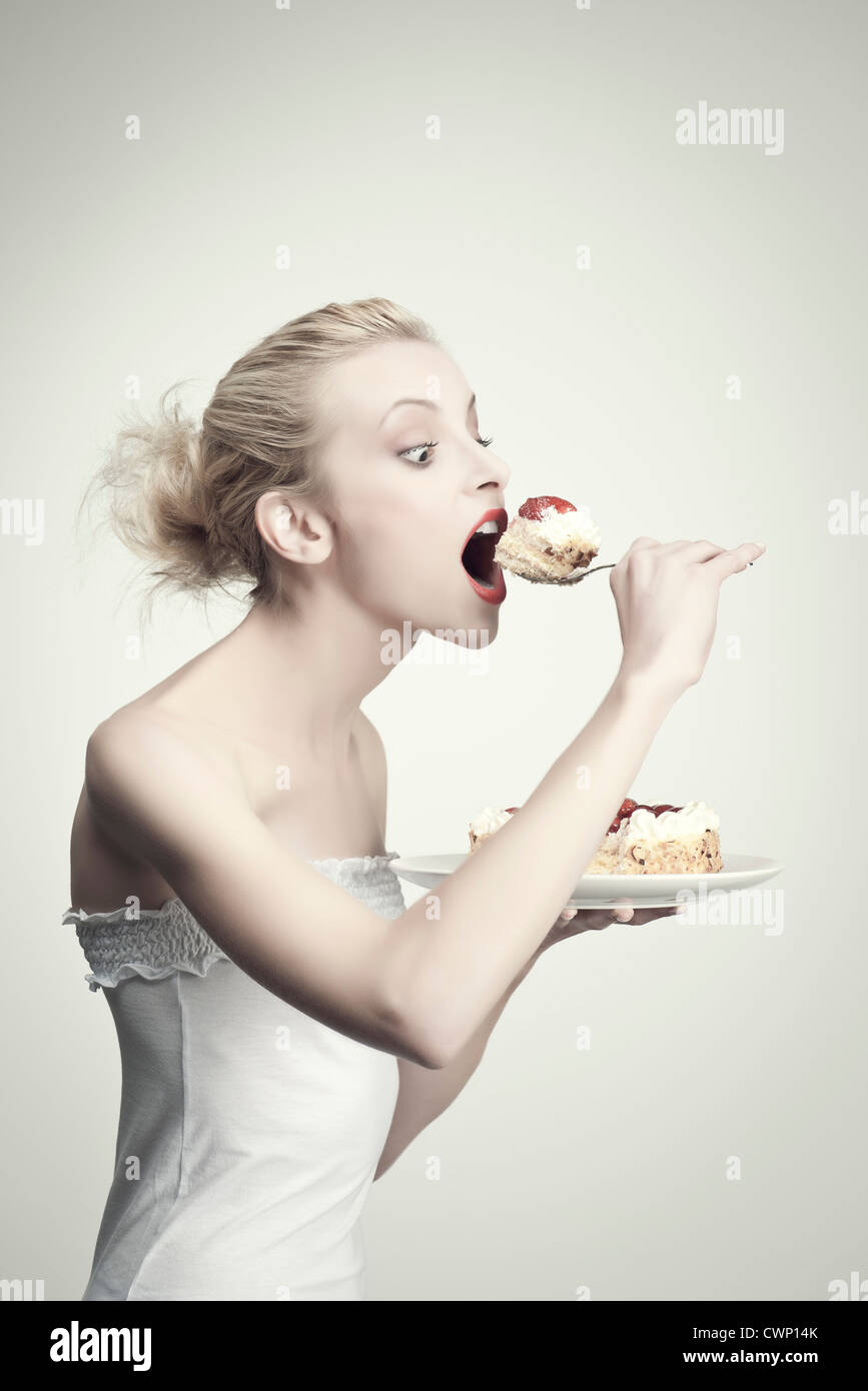 Junge Frau essen Kuchen, Seitenansicht, Porträt Stockfoto