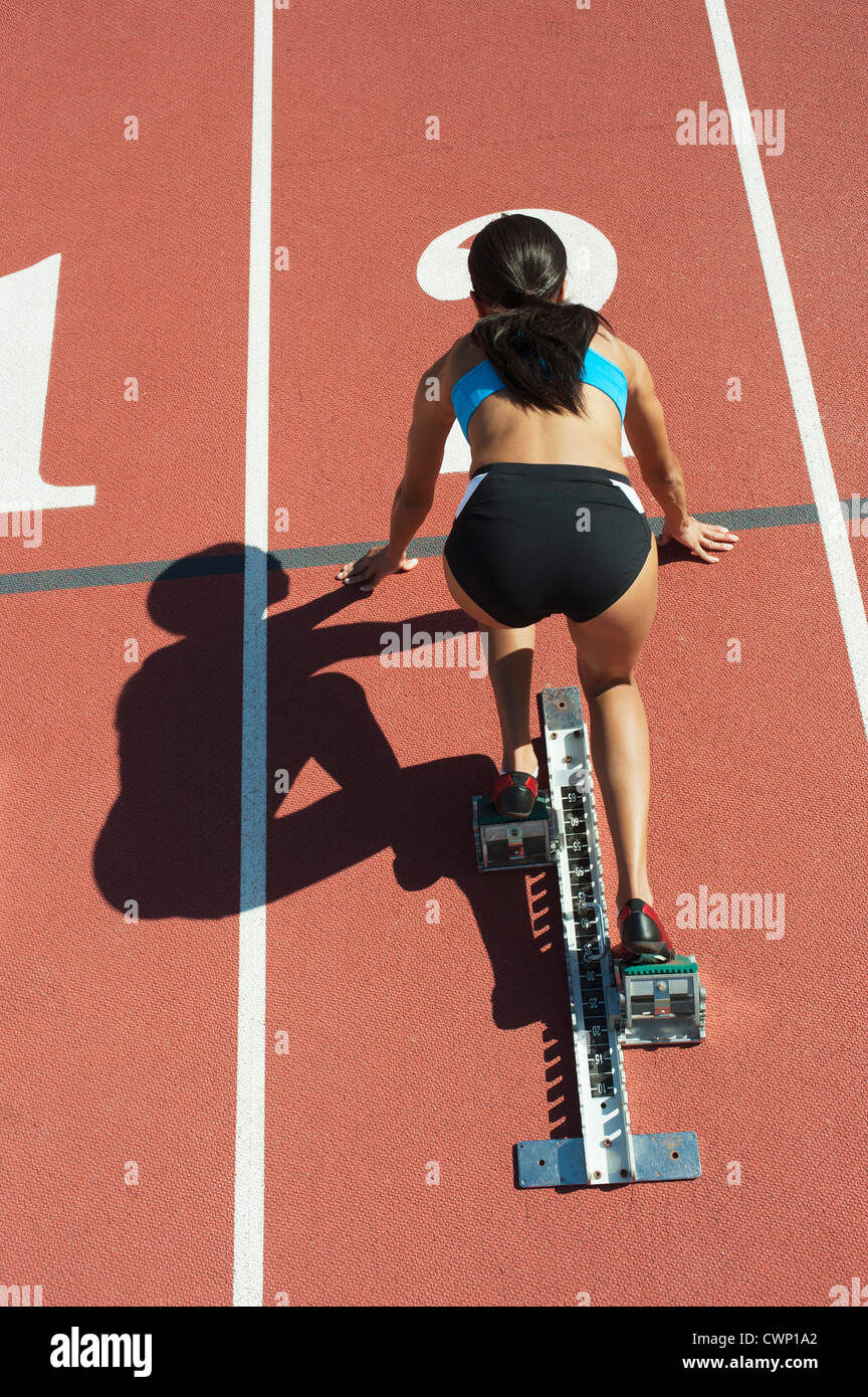 Sportlerin in Startposition auf Laufstrecke, Rückansicht Stockfoto