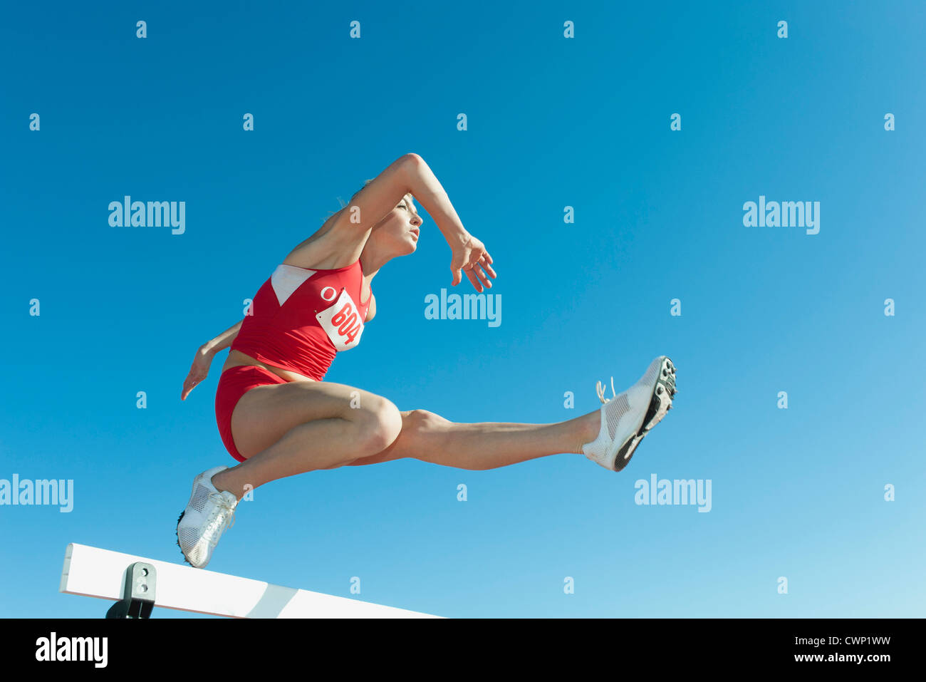 Famale Athleten springen über die Hürde, niedrigen Winkel Ansicht Stockfoto