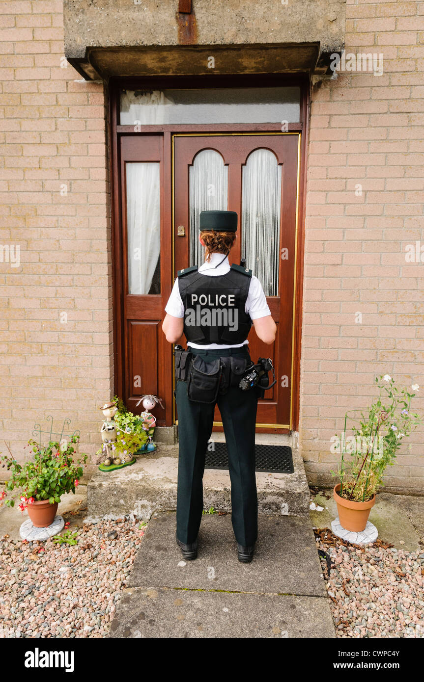 Polizistin wartet vor der Tür eines Hauses Stockfoto