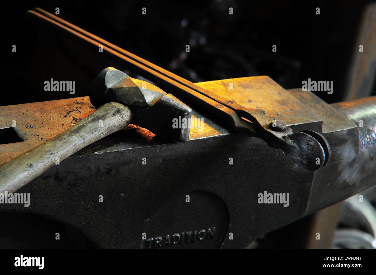Ein Hammer und ein paar Zangen auf einem Amboss in einer Schmiede Stockfoto