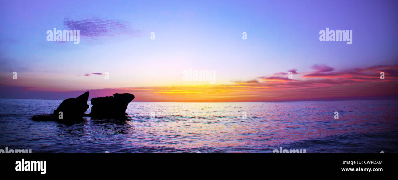Bild von romantischer lila Sonnenuntergang über Seelandschaft, friedliche Ozean Landschaft, schöne Felsen im Abend Meer, ruhiges Herbstwetter Stockfoto