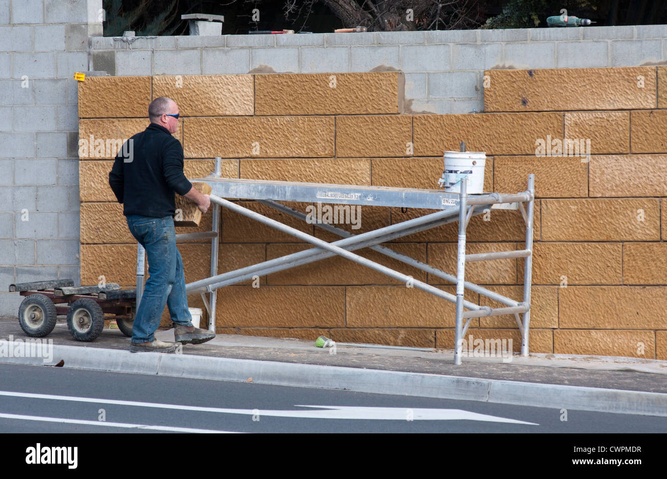 Mann baut eine große Sandsteinmauer Stockfoto