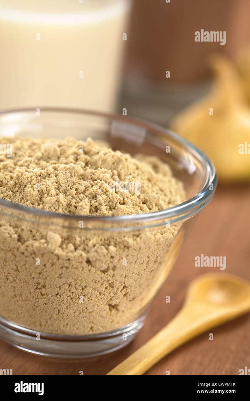 Pulverisierte Maca oder peruanischer Ginseng (lat. Lepidium Meyenii) in Glasschale mit Milchschokolade, Getränk und Maca Wurzeln in den Rücken Stockfoto