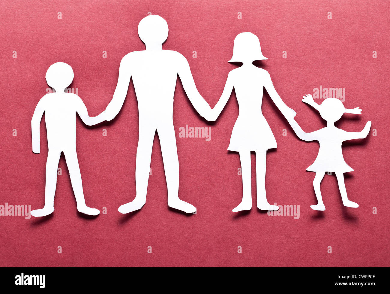 Pappfiguren der Familie auf einem roten Hintergrund. Das Symbol der Einheit und des Glücks. Stockfoto