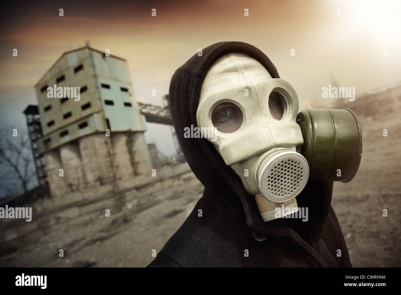 Mann in schützende Gasmaske in der Nähe der Industrieanlage bei radioaktiven Sonnenuntergang. Künstlerisch Farben und Korn hinzugefügt Stockfoto