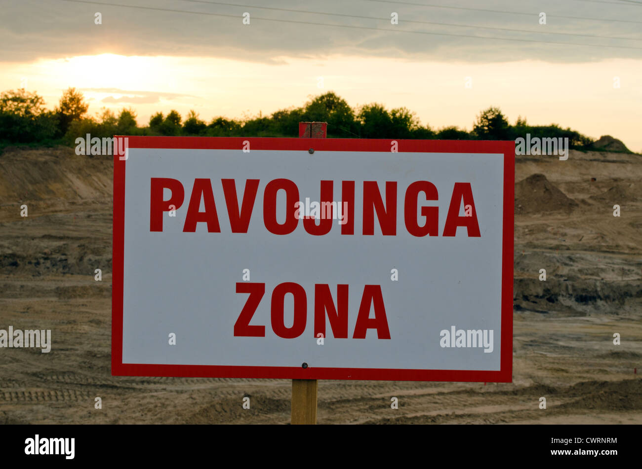 Litauische Warnschild Danger Zone unter Baustelle und Sonnenuntergang. Stockfoto