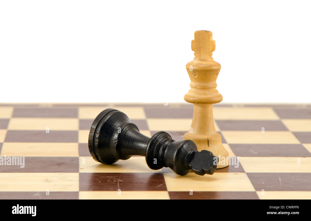 Schwarz Schach König liegen in der Nähe von Gewinner weiß auf Schachbrett isoliert auf weiss. Stockfoto