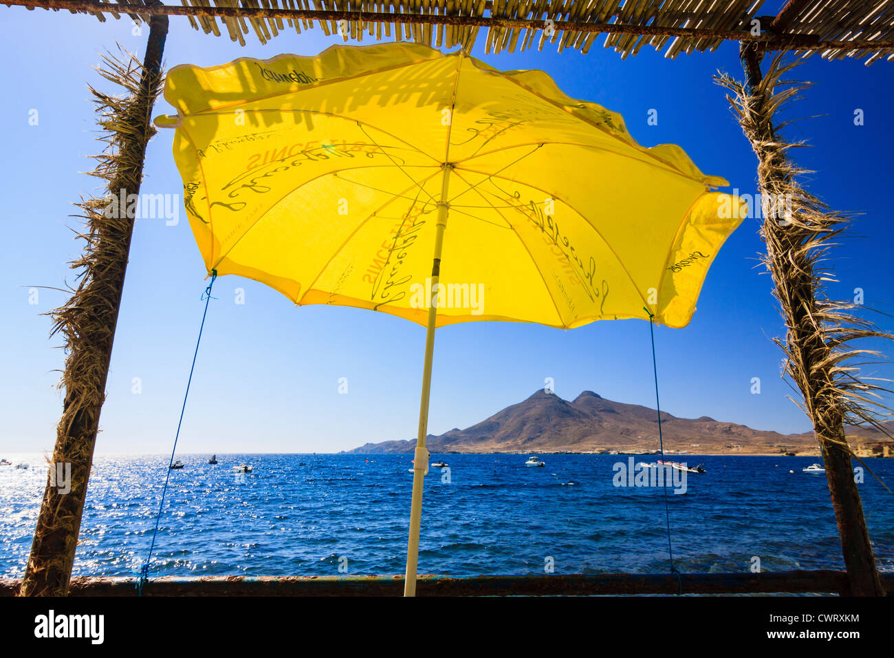 Gelbe Sonnenschirm und Vulkane im Isleta del Moro, Cabo de Gata natürlichen park, Almeria, Andalusien, Spanien Stockfoto