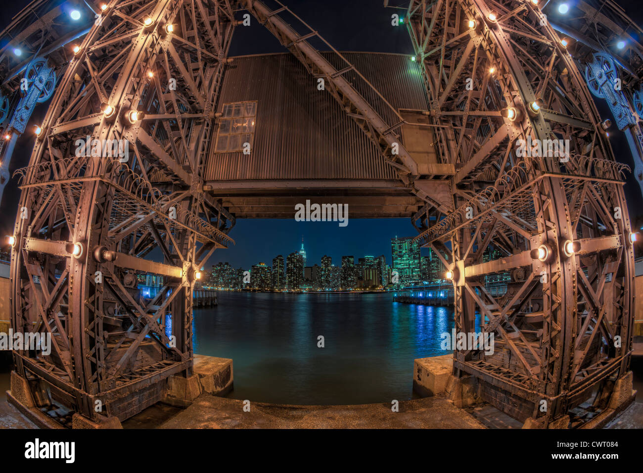 Die Nacht Skyline von Manhattan umrahmt von einer der die Portalkräne über den East River in Gantry Plaza State Park. Stockfoto