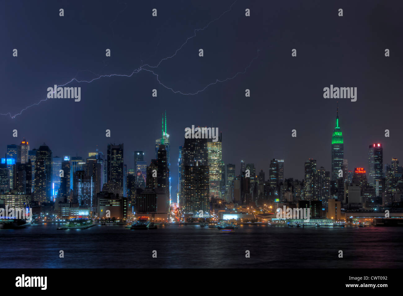 Ein Forked Blitz erhellt den Nachthimmel hinter der Skyline von Midtown während eines Gewitters Sommer in New York City. Stockfoto