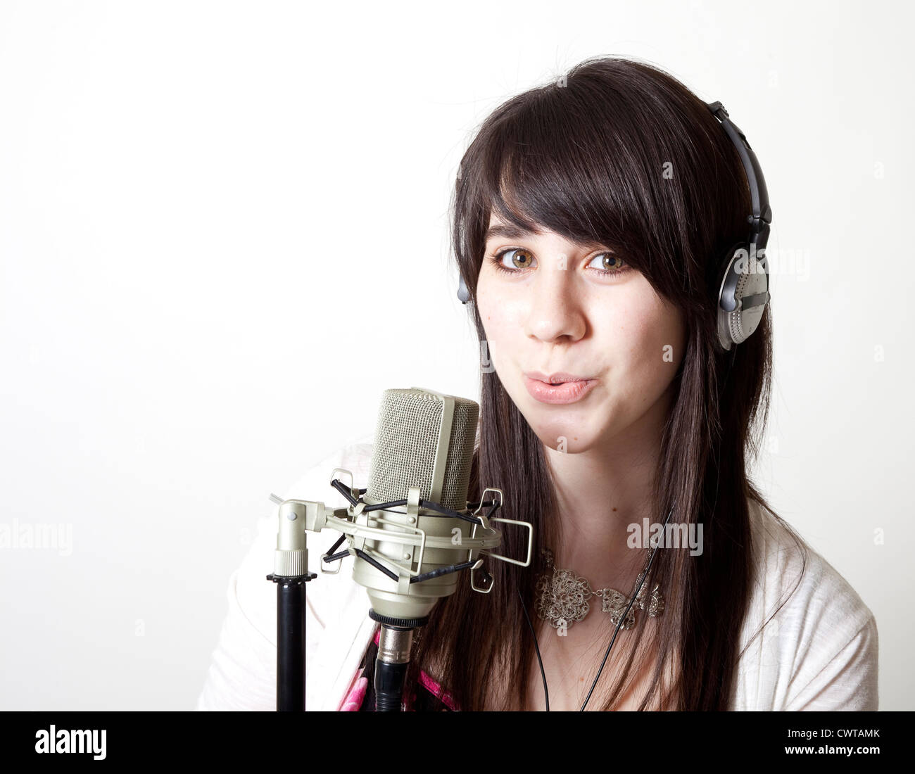 Ein hübsches Mädchen im Kopfhörer macht melodiöse Töne in ein Mikrofon. Stockfoto