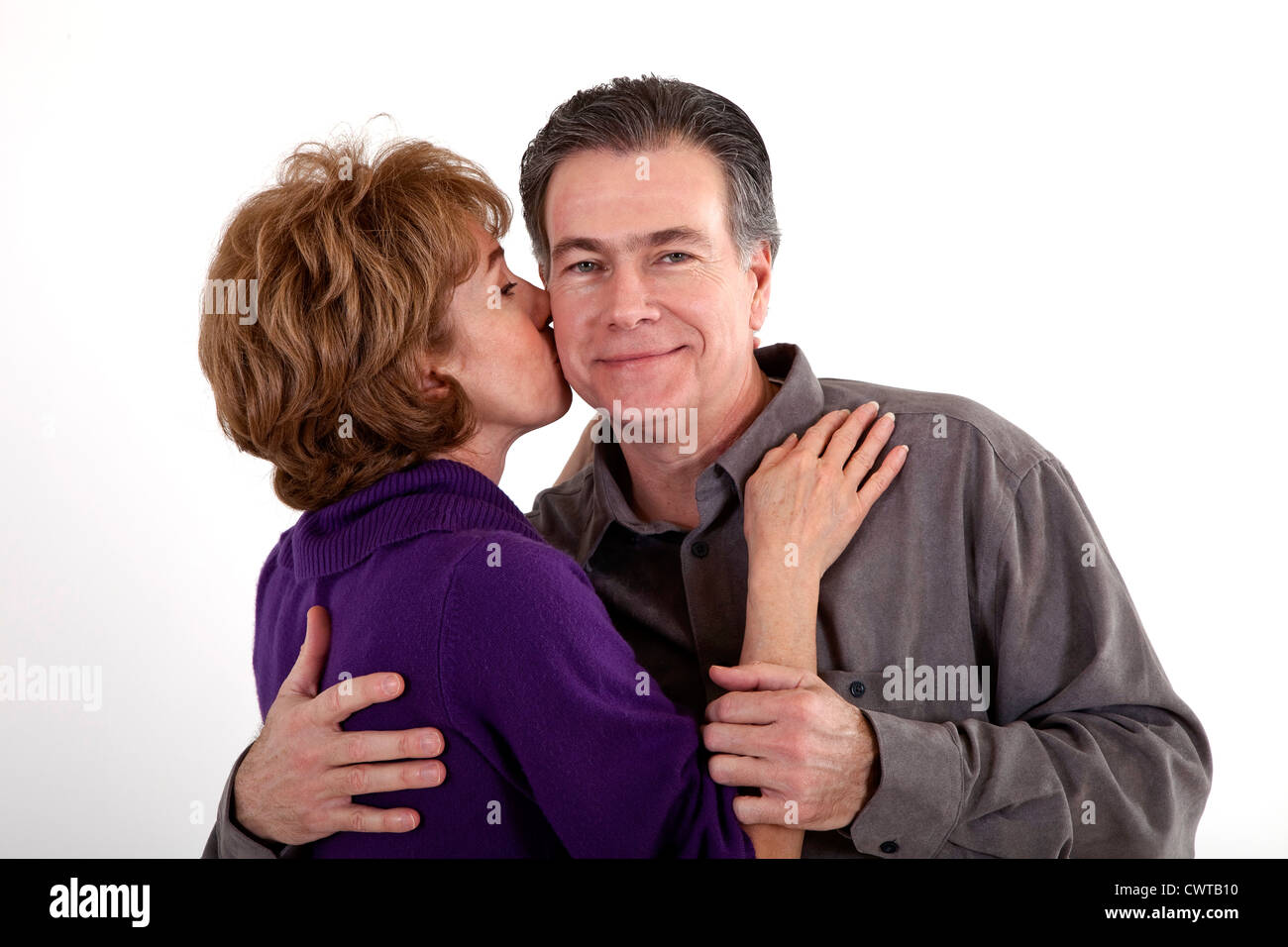 Eine Frau gibt ihrem Partner ein Küsschen auf die Wange, während er anerkennend lächelt. Stockfoto