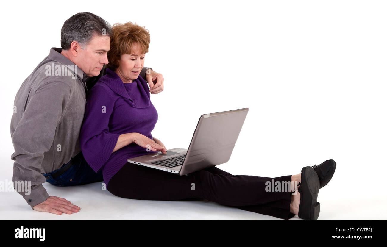 Ein älteres Paar sitzt auf einem weißen Hintergrund Blick auf etwas auf einem Laptop. Stockfoto