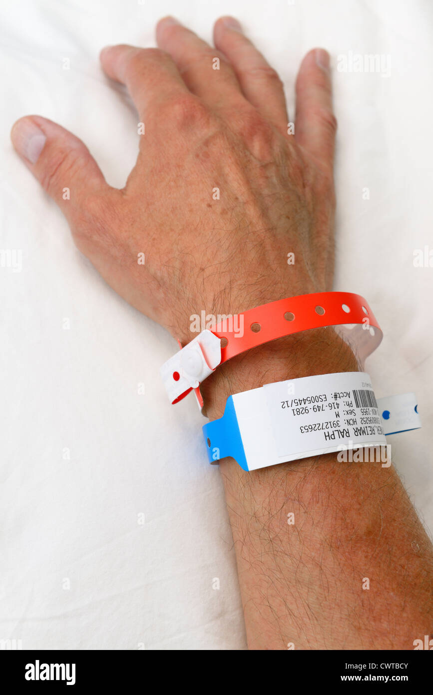 Einen Mann auf einem Krankenhausbett mit Identifikation Armbänder Stockfoto