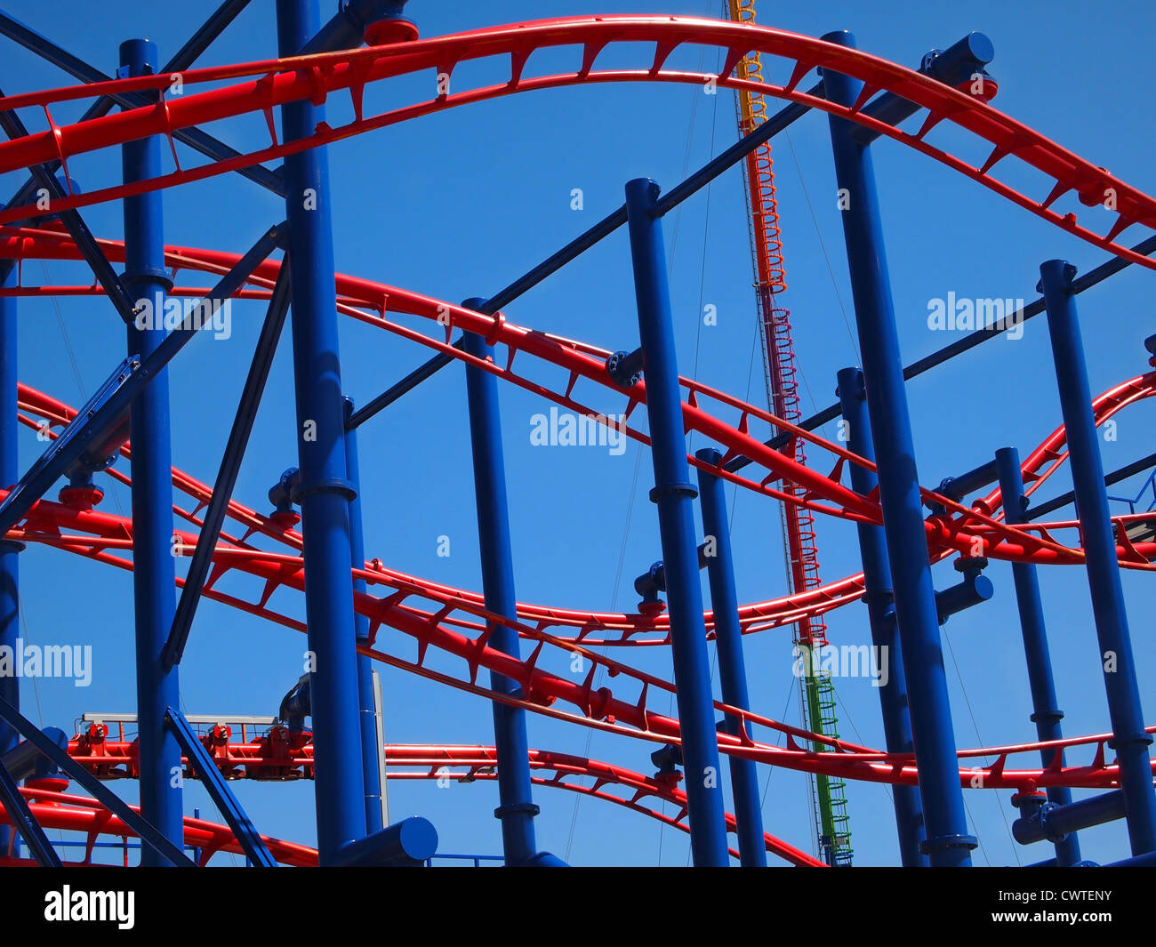 Nahaufnahme in die Spuren einer kurvenreichen blaue und rote Achterbahn vor blauem Himmel. Stockfoto