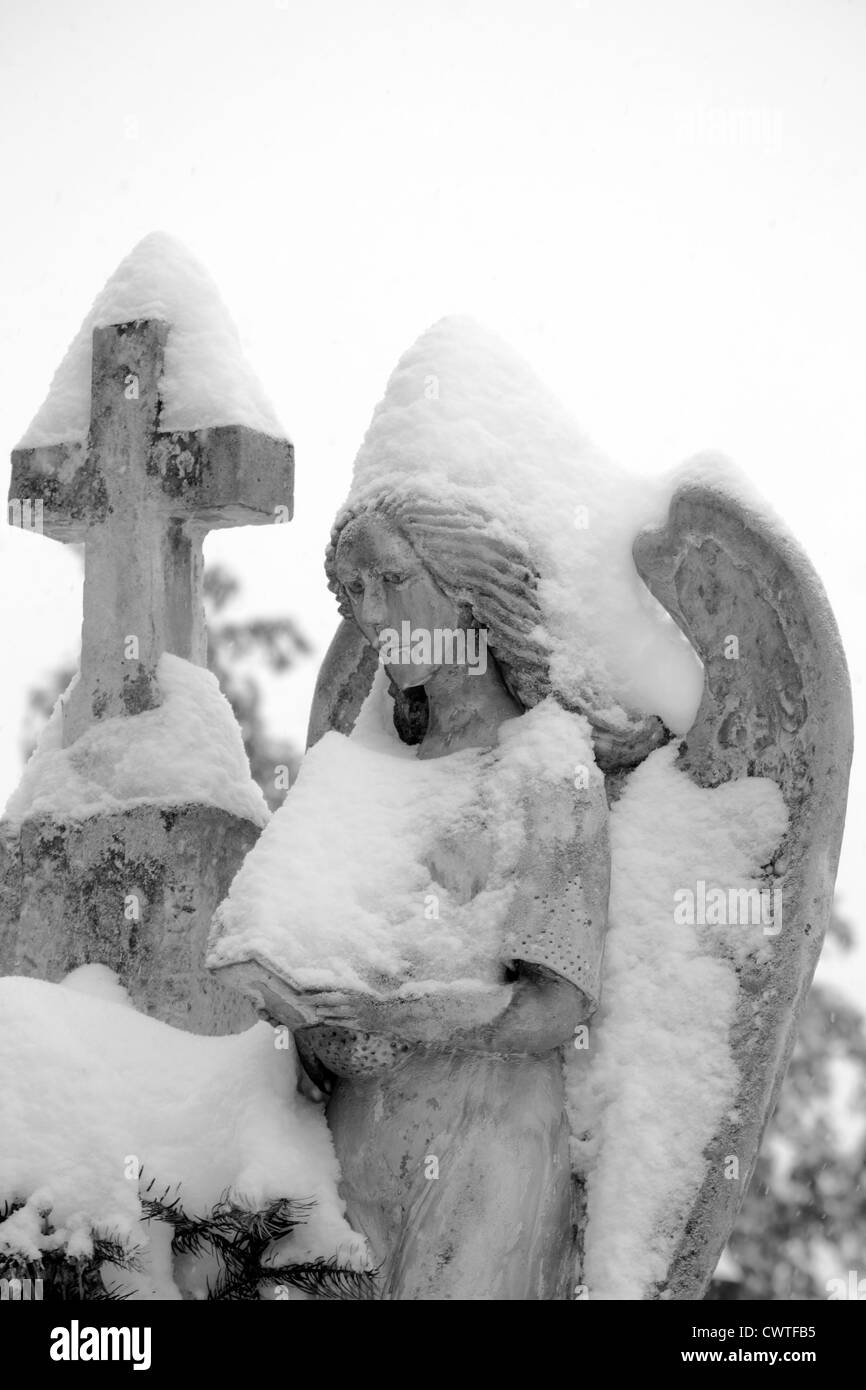 schwerer Stein Engelsstatue mit Schnee bedeckt Stockfoto