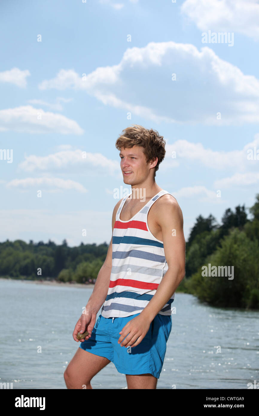 Junger Mann in Sommerkleidung am Fluss Isar, München, Bayern, Deutschland Stockfoto
