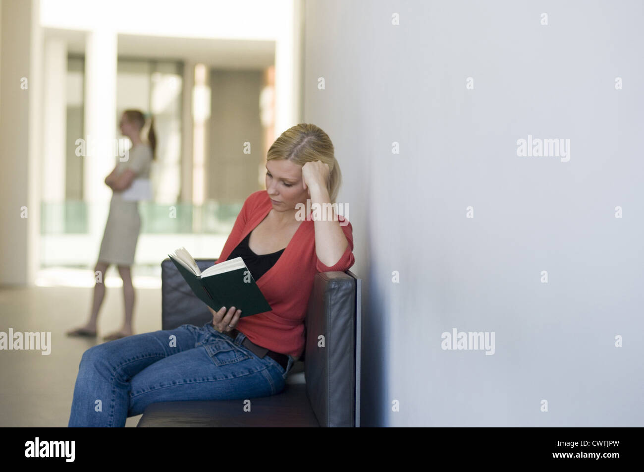 Blonde junge Frau Buch auf couch Stockfoto