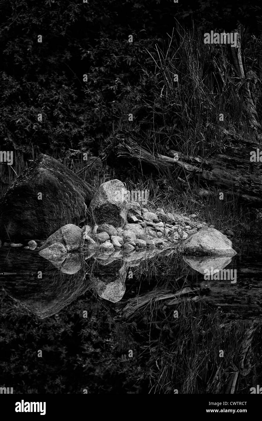 Felsigen Reflexionen, stilles Wasser reflektiert Felsen am Rand des Wassers, schwarz / weiß-Bild. Stockfoto