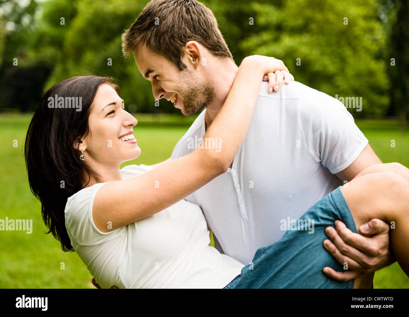 Glückliches junges Paar - Mann trägt Frau das Leben zu genießen Stockfoto