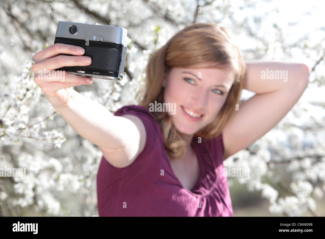 Frau unter Bild von sich selbst vor blühenden Baum Stockfoto