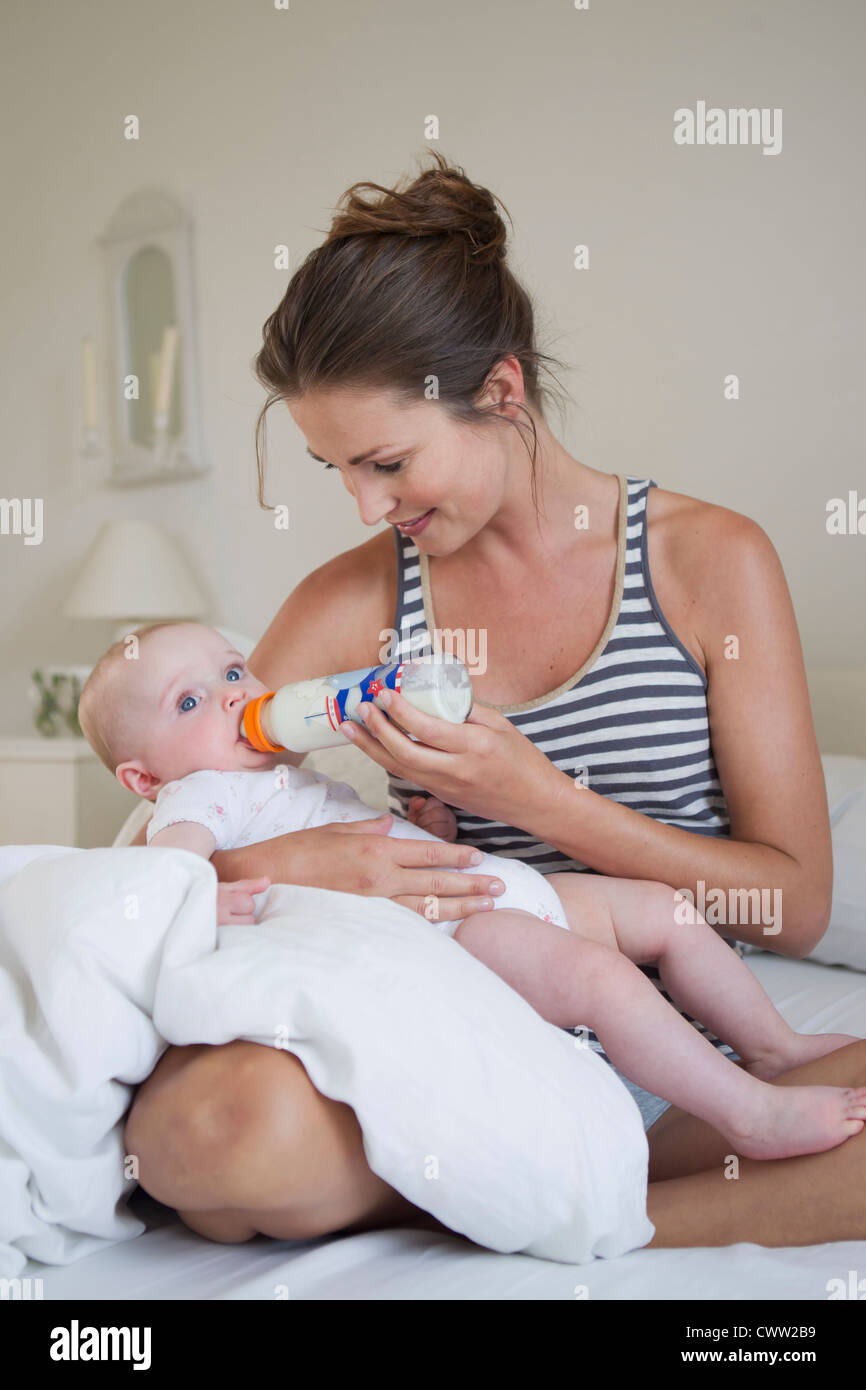 Lächelnde Mutter mit der Flasche füttern baby Stockfoto