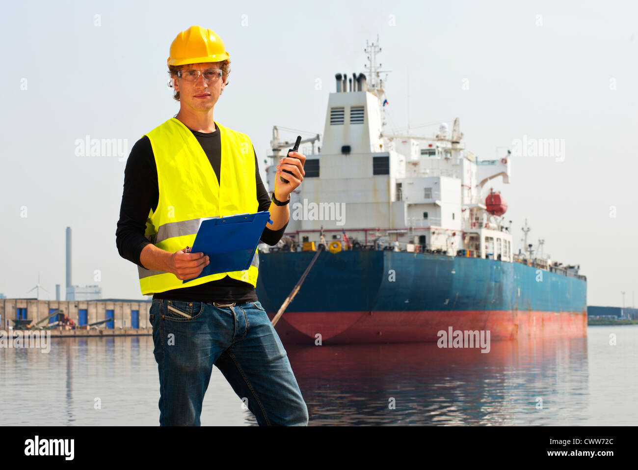 Porträt von Docker mit Zwischenablage und Cb Radio vor einem großen Öltanker Stockfoto