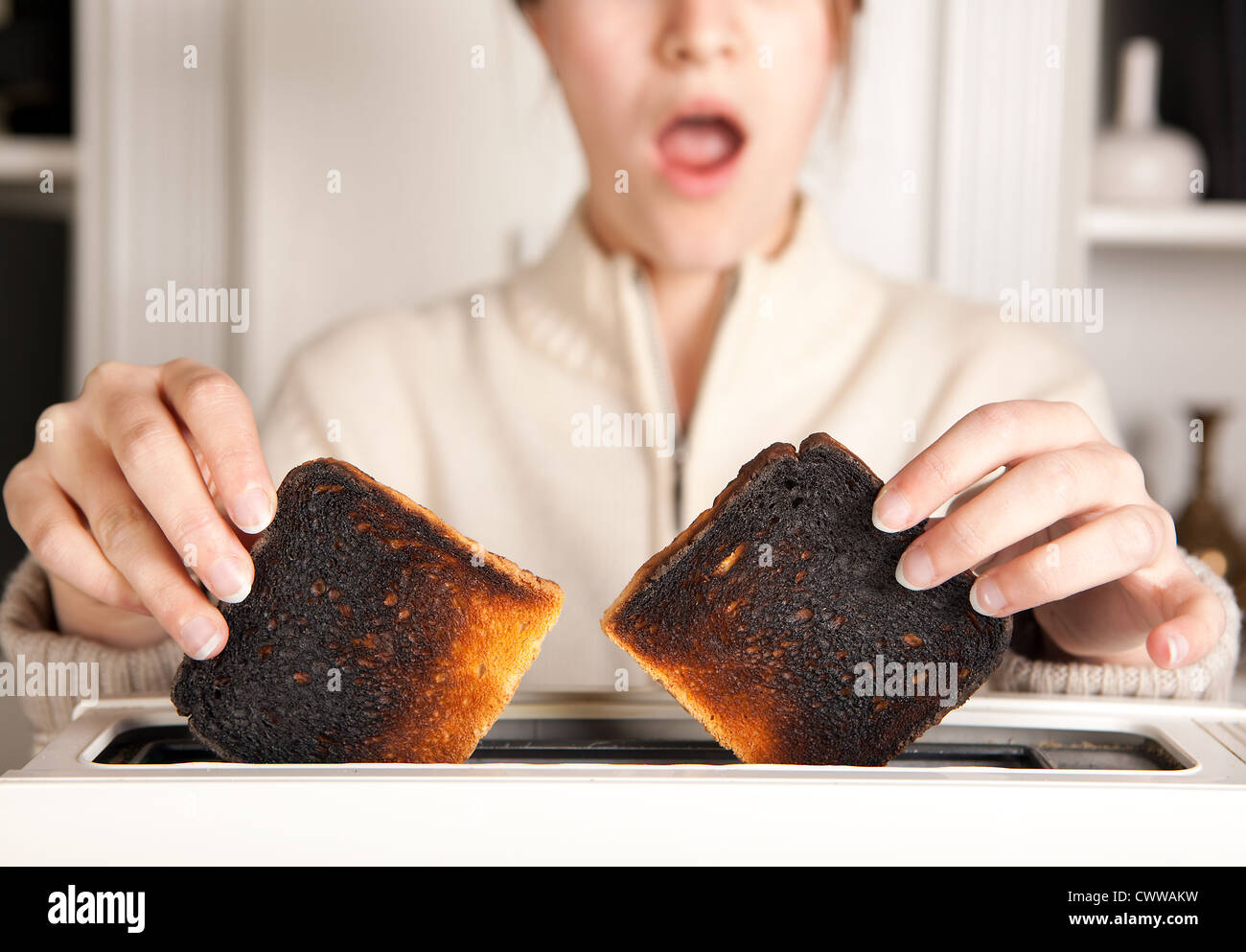 Hände einer Frau, die Einnahme von verbranntem Toast aus einem toaster Stockfoto